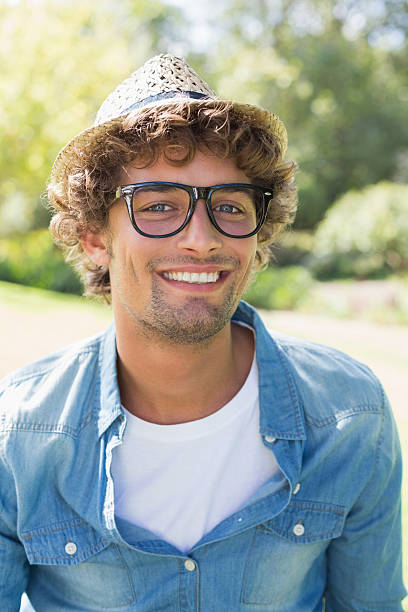 istock Hip young man sitting on park bench smiling at camera 498553321