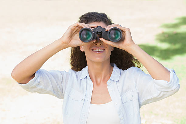 istock Pretty woman standing in the park looking through binoculars 498553325