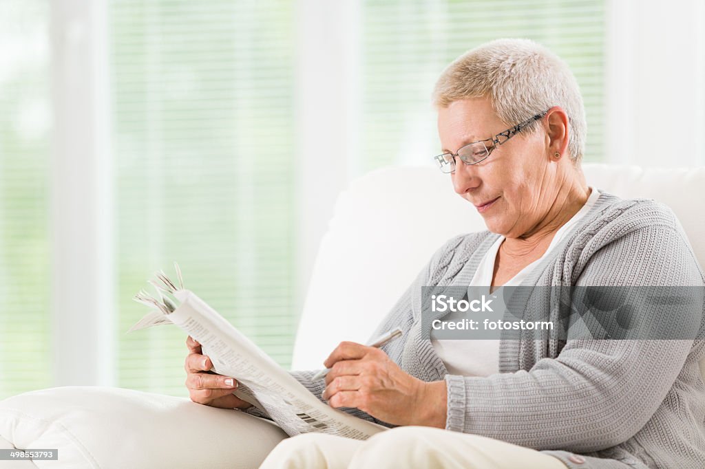 Senior woman reading newspapers Senior woman reading newspapers at home. 60-64 Years Stock Photo