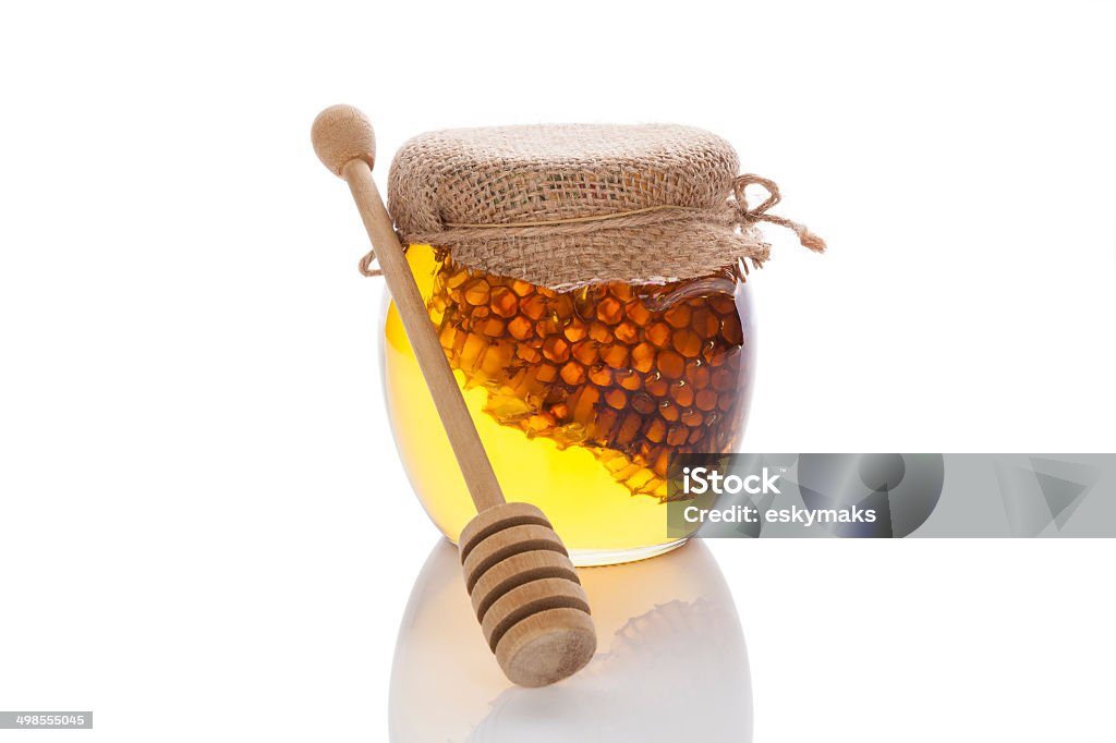 Honey jar with wooden dipper. Honey in glass jar with wooden dipper and honey comb isolated on white background. Organic bee honey. Alternative Medicine Stock Photo