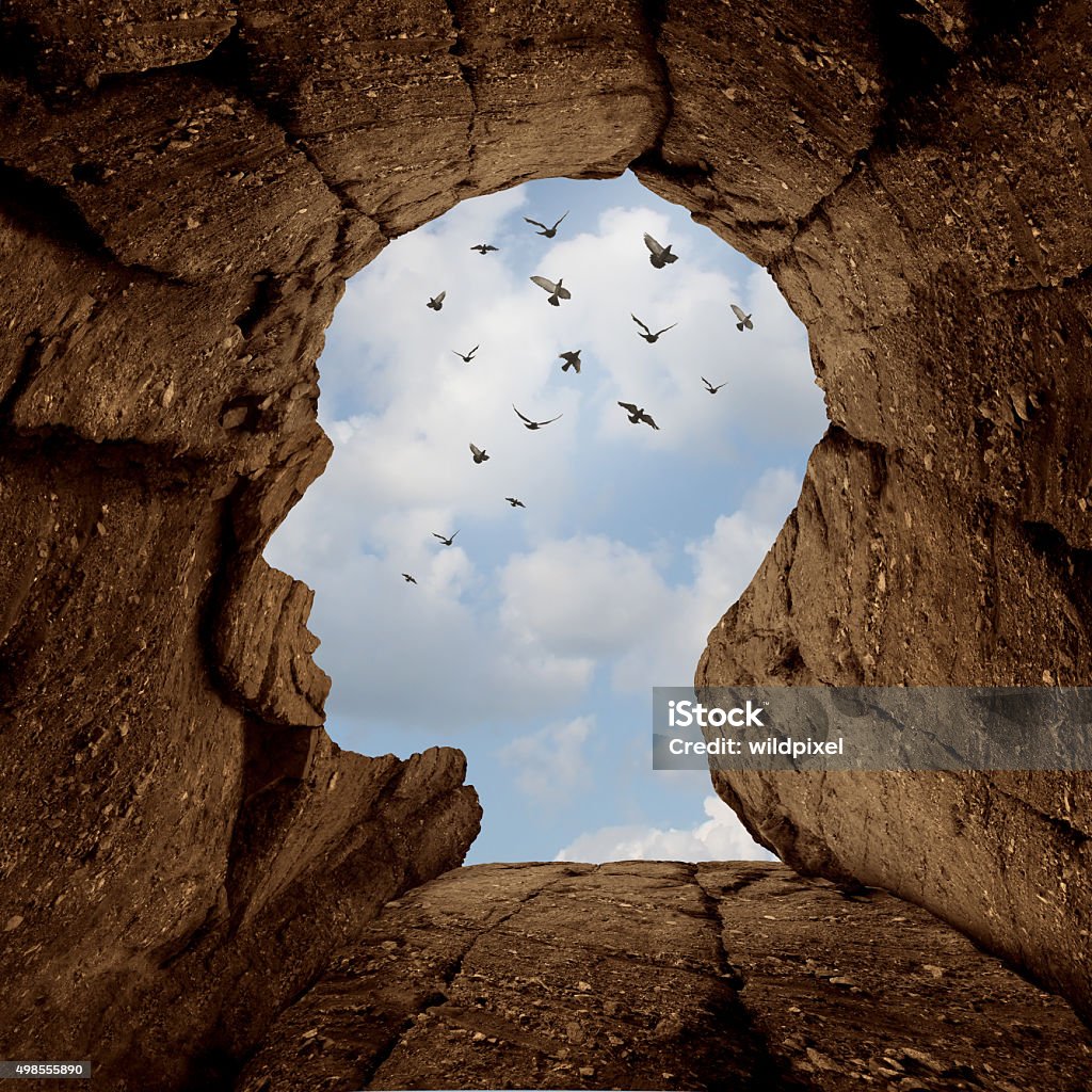 Imagination And Discovery Concept Imagination and discovery concept as a rocky cliff with an opening on top shaped as a human head as a new life metaphor and success motivation symbol with a group of birds flying high in the sky. New Life Stock Photo