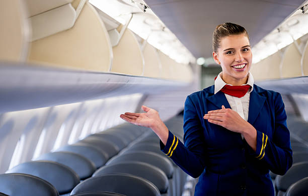 Flight attendant Friendly flight attendant gesturing in an airplane crew stock pictures, royalty-free photos & images