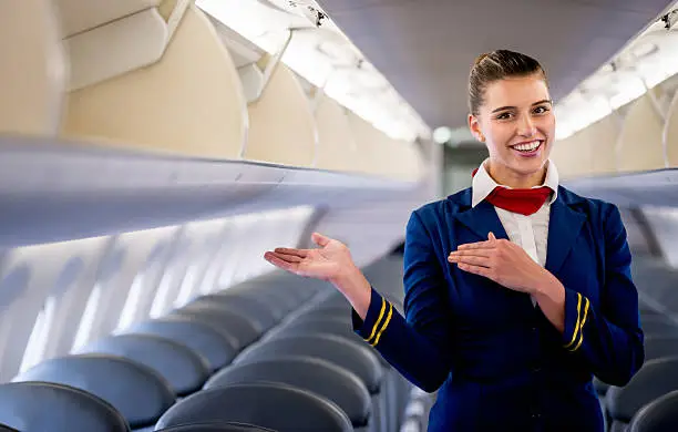 Friendly flight attendant gesturing in an airplane