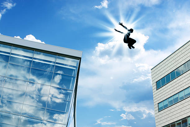 Man jumping over building roof against blue sky background