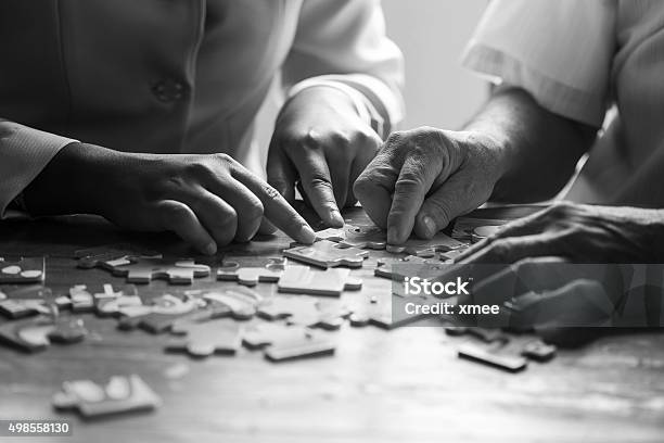 Elder Care Nurse Playing Jigsaw Puzzle With Senior Man Stock Photo - Download Image Now