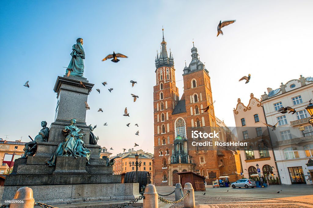 Old city center view in Krakow Old city center view with Adam Mickiewicz monument, St. Mary's Basilica and birds flying in Krakow on the morning Krakow Stock Photo
