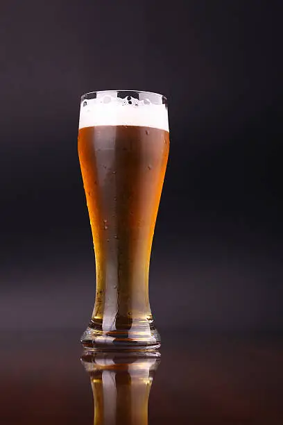 Glass of light beer over a dark background