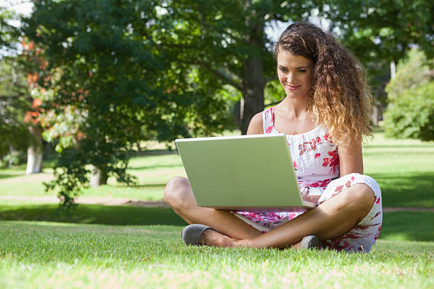 istock Pretty woman sitting in the park using laptop 498567293