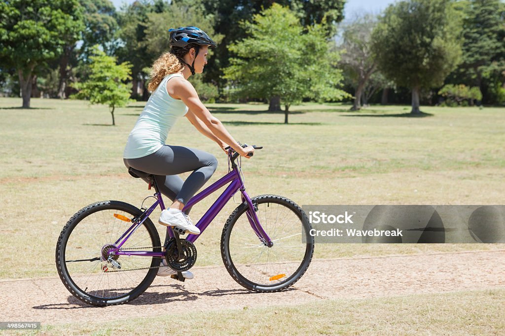 Fit woman riding her bike through the park Fit woman riding her bike through the park on a sunny day 30-39 Years Stock Photo