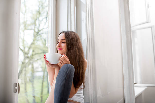 istock Young and cute lady dreaming on windowsill with cup 498567851