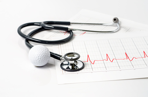 stethoscope and golf ball on white background