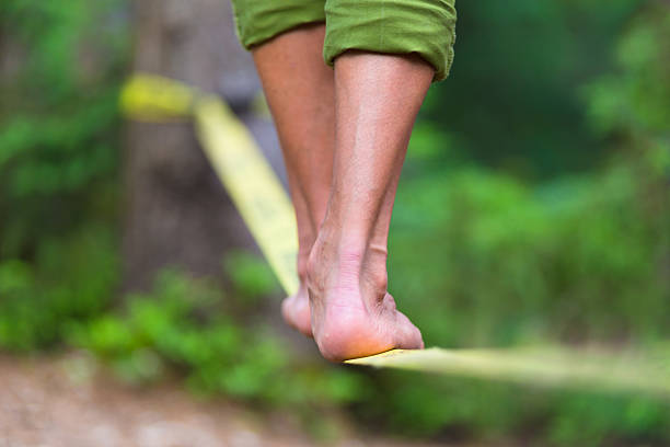 Slack line in the nature. Slacklining is a practice in balance that typically uses nylon or polyester webbing tensioned between two anchor points. tightrope stock pictures, royalty-free photos & images
