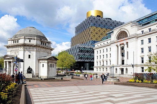 Birmingham, United Kingdom - May 14, 2014:  View of the Hall of Memory (to the left), Baskerville House (to the right) and the new Library of Birmingham in Centenary Square to the rear with People walking through towards the shopping centre, Birmingham, England, UK, Western Europe.