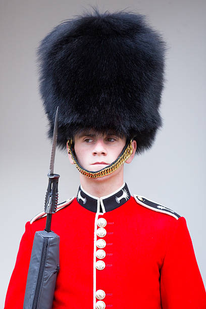 London, United Kingdom - May 23, 2014: An iconic  Guard with a funny face stands on guard duty at the Tower of London. The bright red tunic and black fur helmet is a trademark of this internationally known regiment.