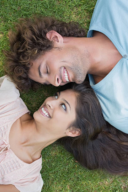 istock Young couple lying on grass smiling at each other 498569883