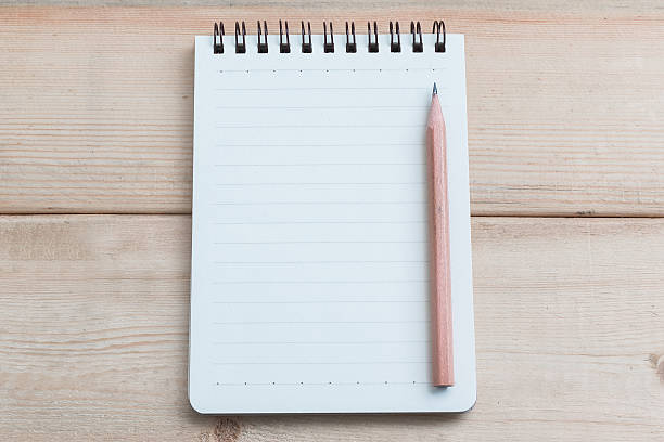 Open blank notepad on wood table background with brown pencil