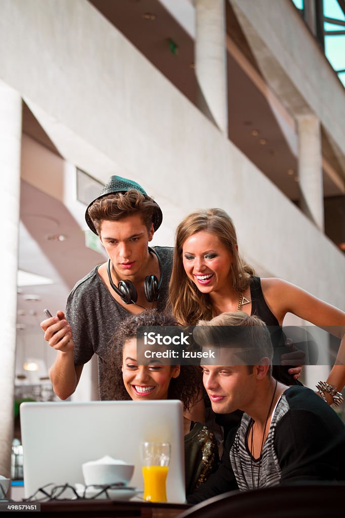 Urban young people using laptop Cheerful young urban people using laptop together. 20-24 Years Stock Photo