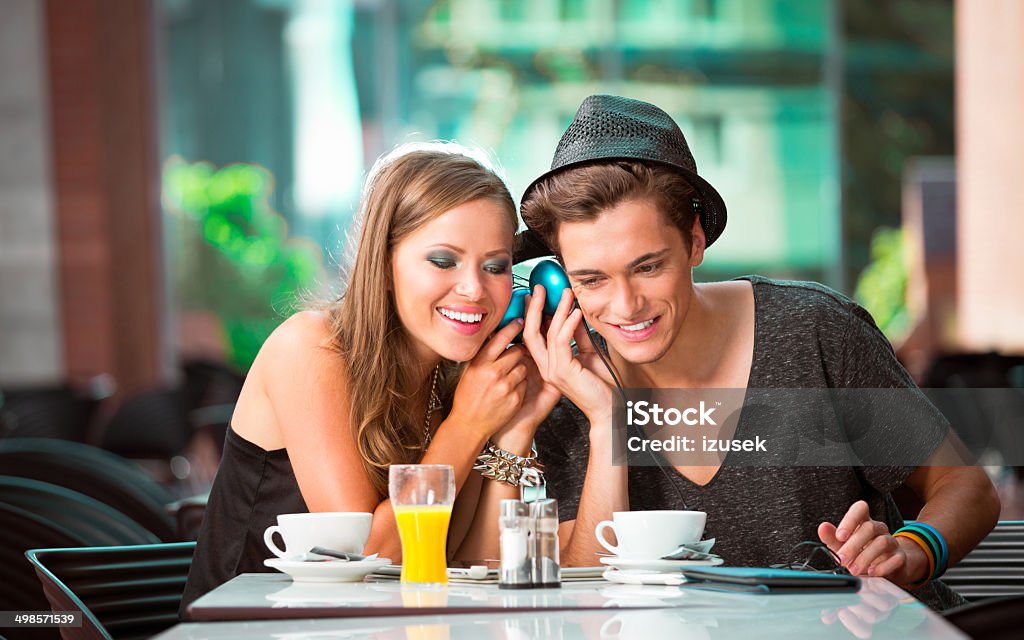 Urban young people in cafe Cheerful young couple sitting in cafe, listen to the music together. 20-24 Years Stock Photo