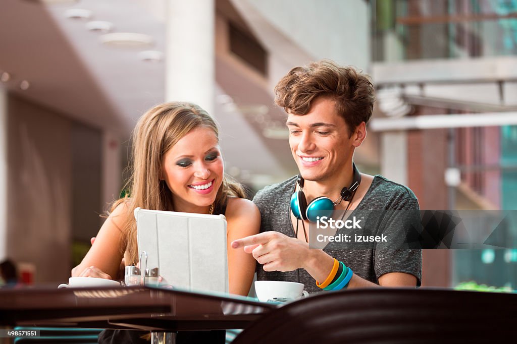 Couple using digital tablet Cheerful young urban people sitting in coffee shop and using digital tablet together. 20-24 Years Stock Photo