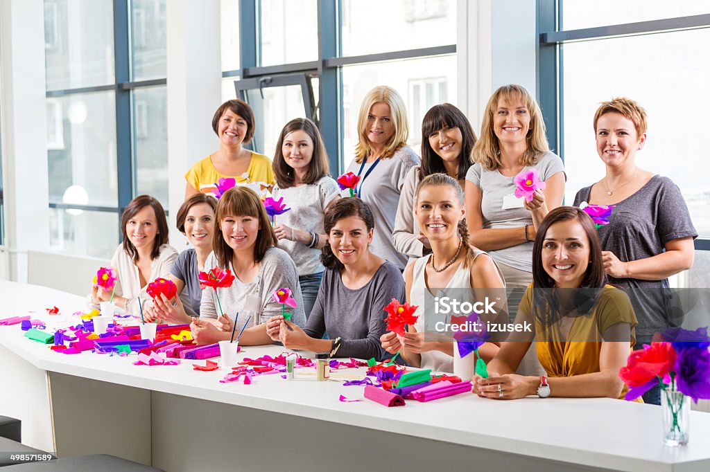 Workshop for women Portrait of group of women attending a workshop, making paper flowers, smiling at the camera. Adult Stock Photo