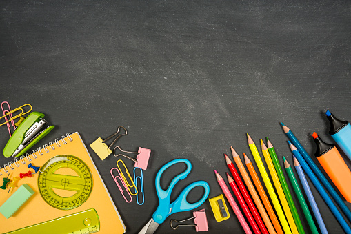 View directly above of a blackboard with school supplies and plenty of copy space in the dark area that kids use at school.