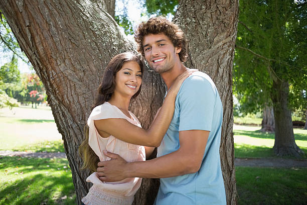istock Young couple standing and embracing by large tree 498572459