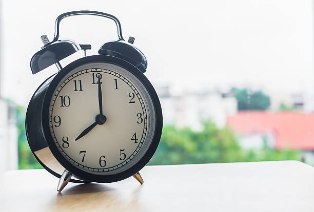 istock Vintage alarm clock on wood table beside window 498572542