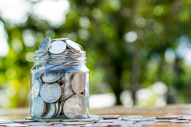 istock Money jar filled with coins on green bokeh 498573328