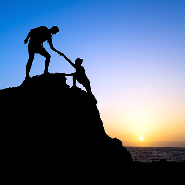 istock Man and woman help silhouette in mountains 498576249