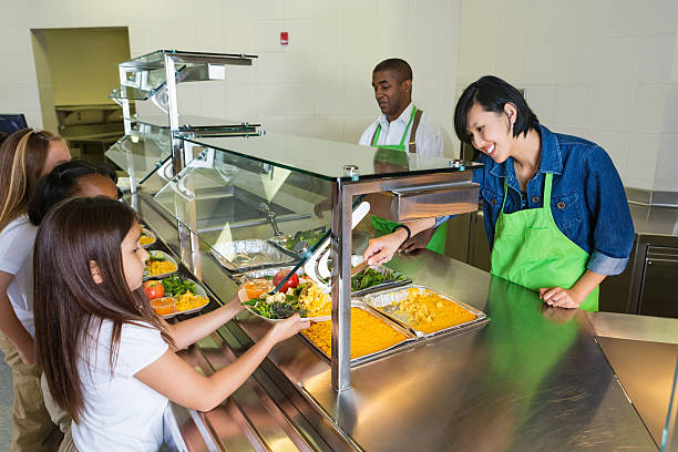 empleado de servicio de comidas que se sirven alimentos sanos a los niños en el almuerzo de dos líneas - tray lunch education food fotografías e imágenes de stock