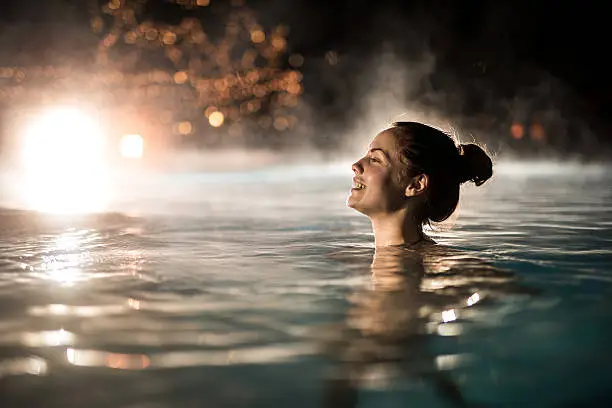 Photo of Happy woman spending a winter night in heated swimming pool.