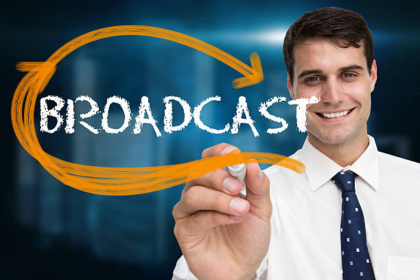 istock Businessman writing broadcast against cityscape on black backgro 498579961