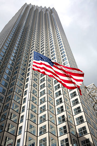 istock US flag waving against building and grey sky 498580385
