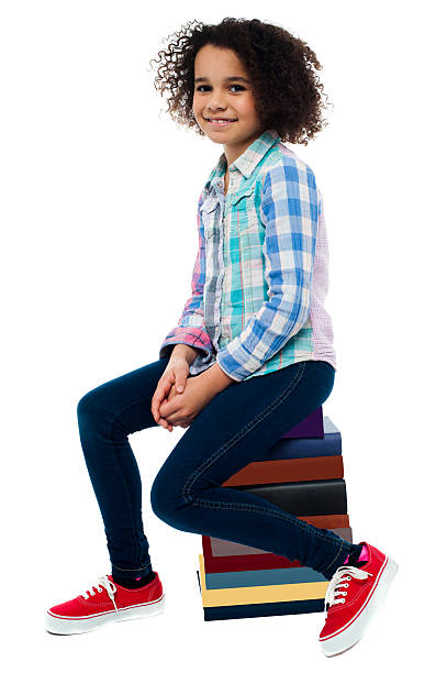 istock Cute school girl sitting on stack of books 498584089