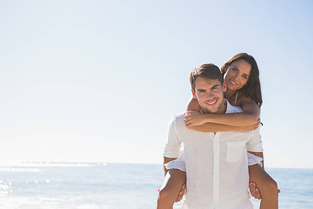 istock Smiling man giving girlfriend a piggy back looking at camera 498597785
