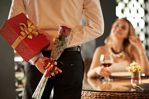 Valentines day Man hiding red rose and gift for his girlfriend behind his back anniversary gifts stock pictures, royalty-free photos & images
