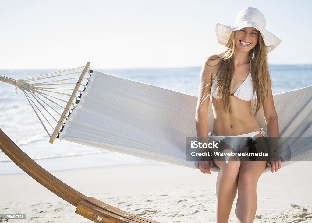 Bonita rubia usando y sunhat bikini sentada en una hamaca - Foto de stock de Adulto libre de derechos