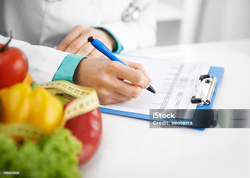 Doctor dietitian writing Doctor nutritionist writing case history in the office. Young woman dietitian prescribing recipe. 2015 Stock Photo