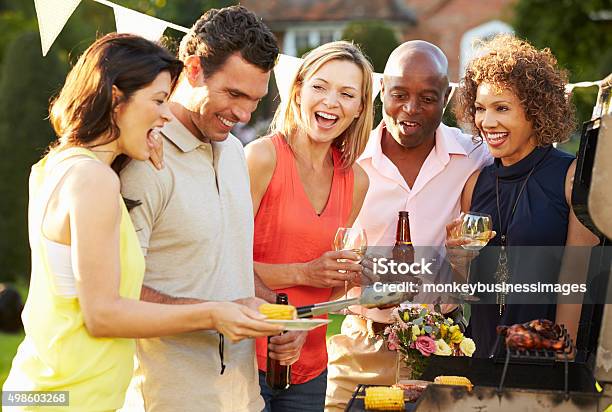 Mature Friends Enjoying Outdoor Summer Barbeque In Garden Stock Photo - Download Image Now