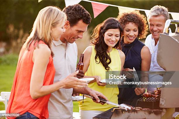 Mature Friends Enjoying Outdoor Summer Barbeque In Garden Stock Photo - Download Image Now