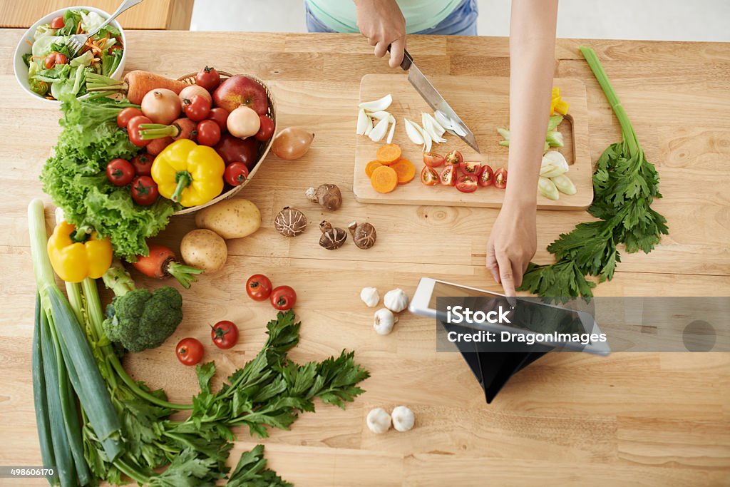 Recipe Woman cooking according to the recipe on digital tablet 2015 Stock Photo
