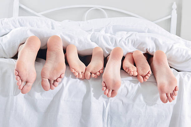 Feet of family in bed Feet of family in bed bed human foot couple two parent family stock pictures, royalty-free photos & images