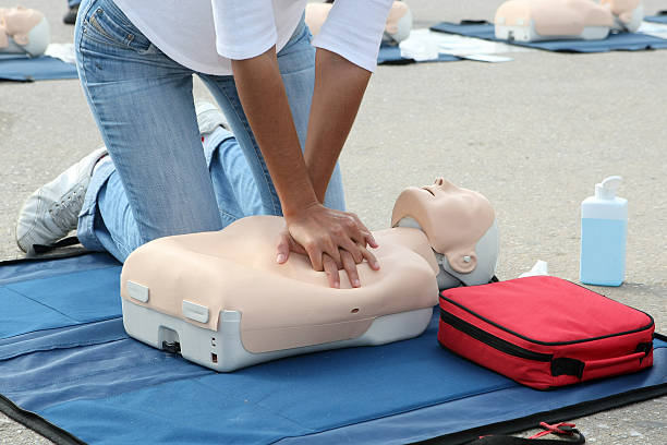 Female instructor showing CPR on training doll Female instructor showing CPR on training doll first aid class stock pictures, royalty-free photos & images