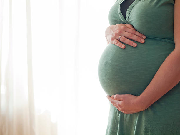 istock Pregnant young woman holding her belly 498615071