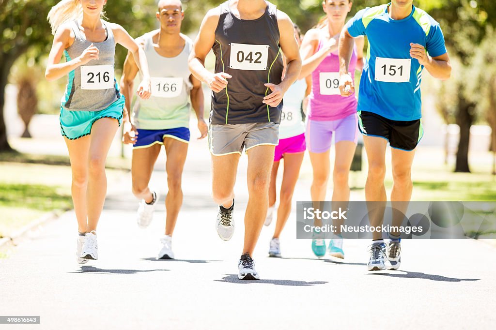 Men And Women Running Marathon At Park Multiethnic men and women running marathon at park. Horizontal shot. Running Stock Photo