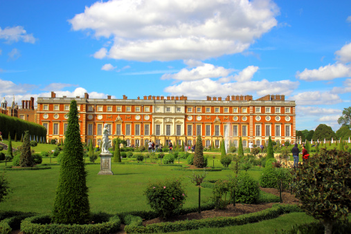 London, England - May 25, 2014: The tourist spend time in the beautiful park and enjoy the sunny weather. Hampton Court Palace was made famous by Henry VIII in the 16th century, who used it as one of his primary residences.