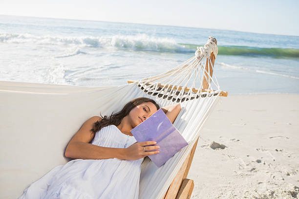istock Woman lying on hammock reading book 498628139
