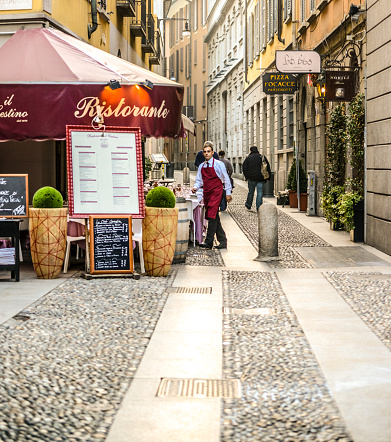 Milan, Italy - October 25, 2012: Restaurant Il Cestino, Milan, Italy. People walking on the street, waiter entering the restaurant. 