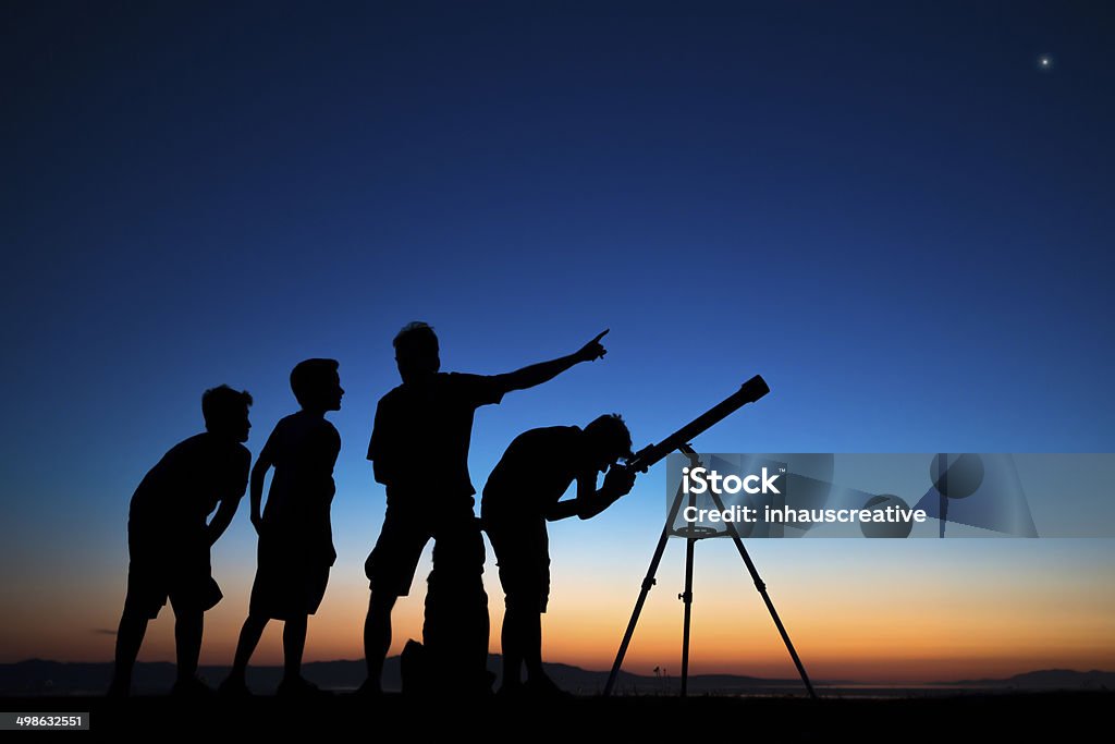 Dad and three sons looking thru a telescope Dad and three sons on a clear night looking thru a telescope Astronomy Stock Photo