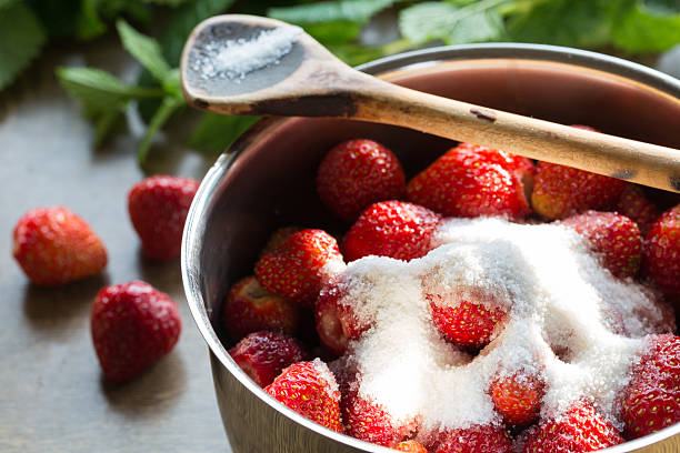 Strawberry jam cooking encore of sugar stock photo